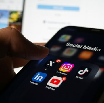 A person holding a smart phone with social media on the screen